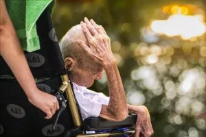 An elderly man in a nursing home facility sitting in his wheelchair.