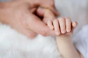 A parent holding his/her baby's hand.