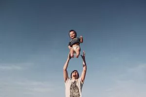 Hombre criando a su bebé bajo el cielo azul.
