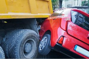 A truck hitting a red car.