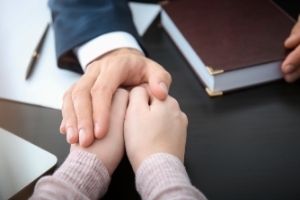 Lawyer holding the hands of a client who lost a loved one.